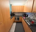 modern kitchen, granite countertops, wooden cabinets, stainless steel appliances, black rug, black countertop