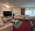 Large living room with couches, television, lamp, table, floor lamp, coffee table, rug, white walls, white ceiling