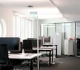 modern office with white walls, black chairs, white desks, computer monitors, glass windows, ceiling lights