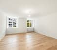 Empty room with hardwood floor, white walls, two windows with view, white ceiling, white radiator