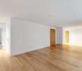 wide empty room, white walls, wooden floor, closets, wooden door