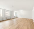 Empty room with hardwood floor, white walls, radiators and windows