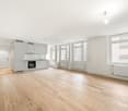 Kitchen: wooden floor, white cabinetry, integrated appliances, windows, radiators, empty space