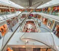 multilevel shopping mall, glass railings, modern art sculpture, many shops, restaurants, cafes
