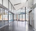 Spacious entrance hall with glass walls and floors, a concrete floor, large ceiling lights.