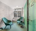 Modern design, two green chairs, small side tables, glass door, concrete wall, glass window