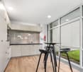 Modern kitchen with wooden floor, large windows, modern furniture, white cabinets, kitchen island with barstools