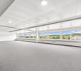 spacious room, high ceiling, gray flooring, large windows with a scenic view, white walls, recessed ceiling lights
