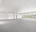 Empty room with grey floor, white walls, ceiling lights, large windows with outdoor view.
