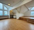 empty room, wooden floor, white walls, large windows, wooden steps, radiators, small kitchen area