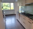 modern kitchen, tiled floor, marble countertops, stainless steel sink, white cabinets, natural light from the window