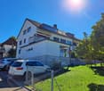 white modern house, multiple windows, parked cars, lawn, tree