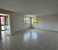 Empty room with tile flooring, white walls, double doors, windows with curtains, balcony access