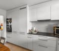 modern kitchen with white cabinets, granite countertop, built-in oven, microwave, island, and a dining table