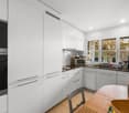 modern kitchen with white cabinetry, black oven, wooden table, tiled floor