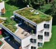 Contemporary house with multiple floors, green roof, large glass windows, and outdoor deck