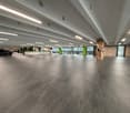 spacious parking area, gray tiled floor, white ceiling, green pillars, parked car, plants, reception desk, windows