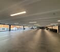 large open space, tiled floor, fluorescent ceiling lights, glass walls, parked cars