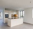 modern kitchen with island, white cabinetry, black countertops, large windows, modern appliances