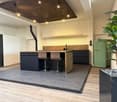 modern kitchen with wooden island, black cabinets, two stools, copper sink, green refrigerator, wooden ceiling with lights, white brick wall, wooden floor