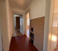 Empty hallway with white walls, red hexagonal tiles, wooden floor, white doors, fireplace