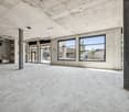 Empty room, concrete floor, large windows, brick wall, metal beams