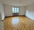 Empty room with white walls, large windows, and a parquet wood floor in a checkered pattern.