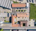 Multiple buildings, large parking lot, roads, open field, cars parked in different areas