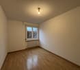 Empty room with wooden floors, white walls, single window with white frame, ceiling lamp, white radiator.