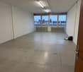 Empty room with white walls and ceiling, concrete floor, radiators, large windows