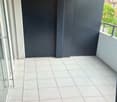 Empty balcony with white tiles, glass doors, black walls, metal railings