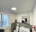 Bathroom with white toilet, sink, mirror, and black tiled floor