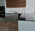 Modern kitchen with white cabinets, gray walls, black countertop, black oven, and double sinks