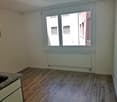 Empty room, wooden floor, white walls, window, radiator, sink, cabinets