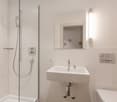 White tiles, shower, sink, toilet, mirror, light, glass enclosure