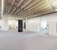 Large open office space with exposed ceiling beams, white walls, and lockers. The space includes a dishwasher and a private washing machine.