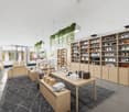 modern shop with open layout, wooden furniture, shelves, hanging plants, tiled floor, carpet, and tables with stacked towels