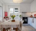 Dining room with a table, chairs, and a kitchen area with a black oven and white cabinets