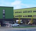 Multi-story commercial building with green and black exterior, parking spaces, and workers on site