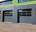 2-story commercial building with green and gray exterior, large windows, and garage doors