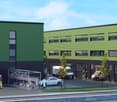 Multi-story commercial building with green and black exterior, parking spaces, and workers on site