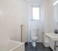 white bathroom, bathtub, sink, toilet, mirror, radiator