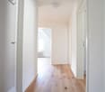 Hallway with wooden flooring, white walls, ceiling light