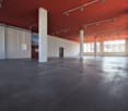 large open space, concrete floor, red ceiling, white walls, track lighting, large windows