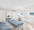 bedroom with bed, mirror, wooden floor, white walls, skylights, plants