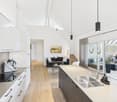 modern kitchen with white cabinets, wooden floor, stainless steel sink, black stove, large windows
