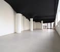 Empty room with white walls, black ceiling, tiled floor, and three white pillars
