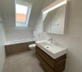 modern bathroom with bathtub, toilet, vanity with sink, mirror, and skylight window