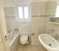 Bathtub, toilet, sink, shower, tile flooring, white walls, white fixtures