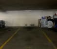 Parking space for one vehicle, grey concrete floor, yellow parking line, storage on side, no vehicles present